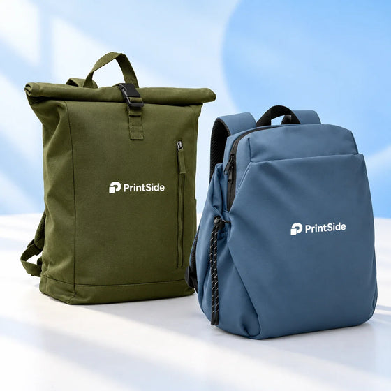 Olive rolltop backpack and blue zip backpack with PrintSide logos.