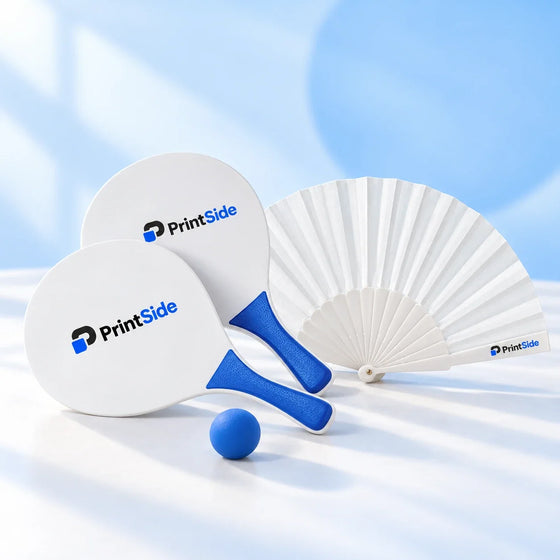 White folding fan beside white-and-blue beach paddles and a blue ball, with PrintSide branding.