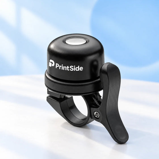 Black bicycle bell with a handlebar clamp and PrintSide logo.