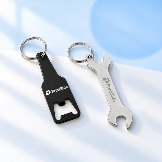 Black bottle-shaped and silver wrench-shaped keyring openers with PrintSide logos.