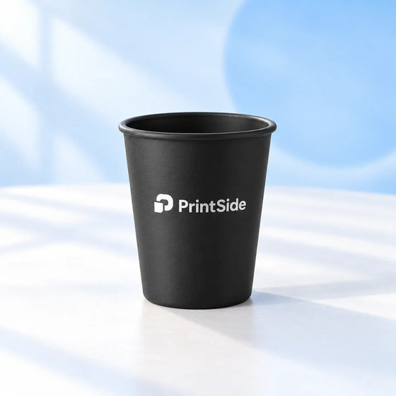 Black reusable coffee cup with a white PrintSide logo.