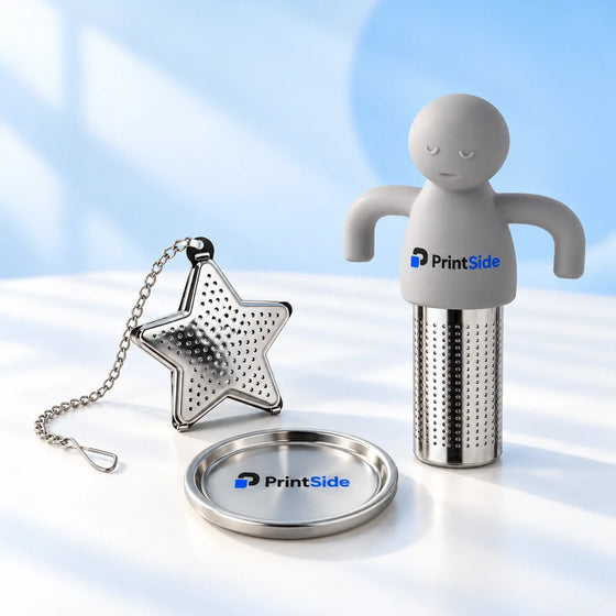 Steel star tea infuser with a drip dish beside a grey figure-shaped tea infuser with PrintSide branding.