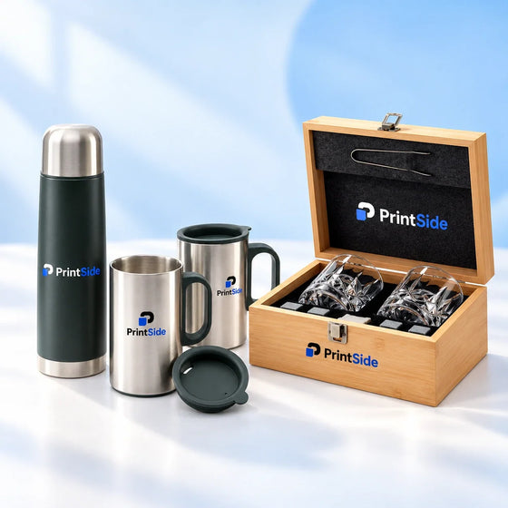 Green vacuum flask and metal mugs beside a wooden gift box with glass tumblers, with PrintSide branding.