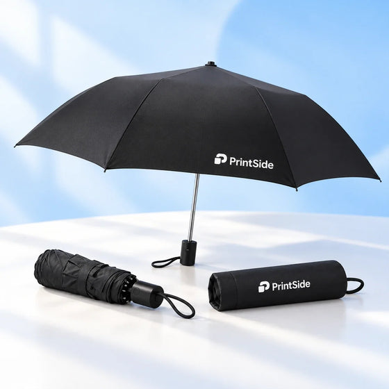 Open and folded black compact umbrellas with a sleeve and PrintSide logos.