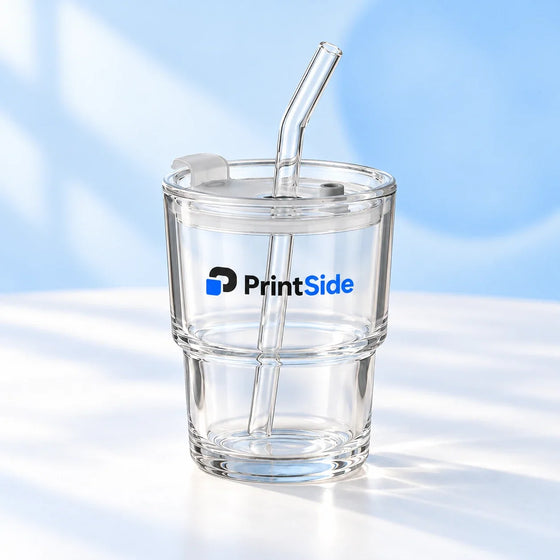 Clear stepped glass tumbler with a lid, bent glass straw and PrintSide logo.