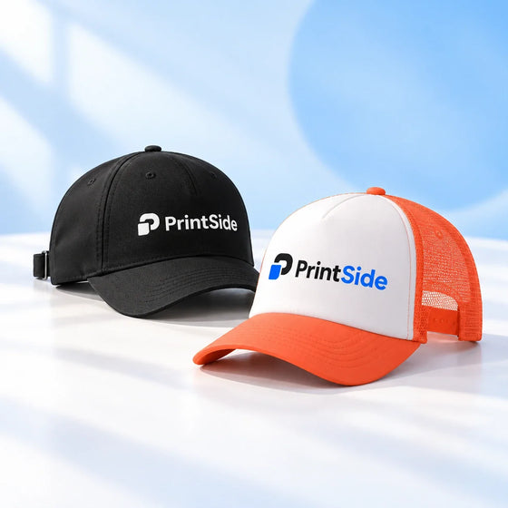 Black baseball cap and orange-and-white trucker cap with PrintSide logos.