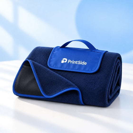 Folded navy fleece blanket with a blue carrying flap and PrintSide logo.