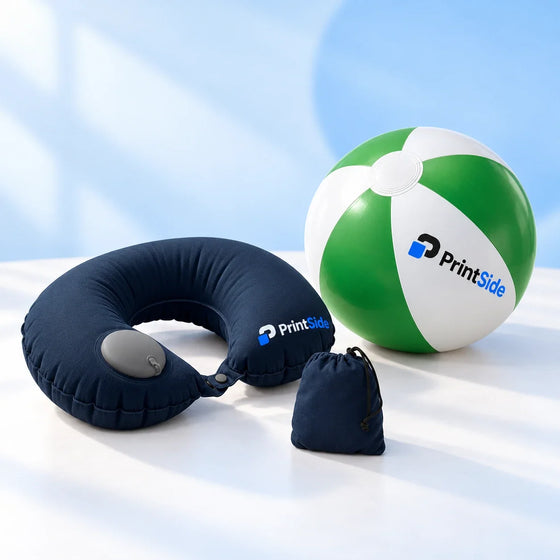 Navy inflatable neck pillow with a pouch beside a green-and-white beach ball with PrintSide logos.