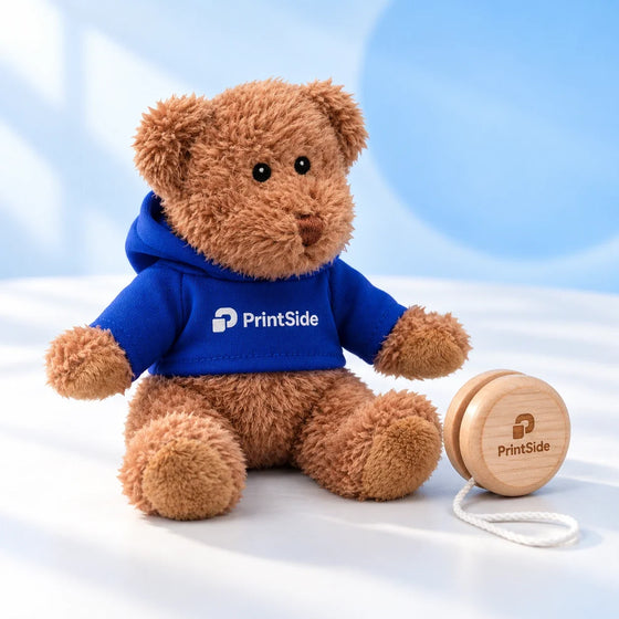Ruskea nalle PrintSide-hupparissa puisen jojon vieressä.