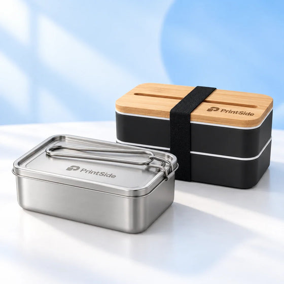 Steel lunch box and black two-tier lunch box with bamboo lid and PrintSide logos.