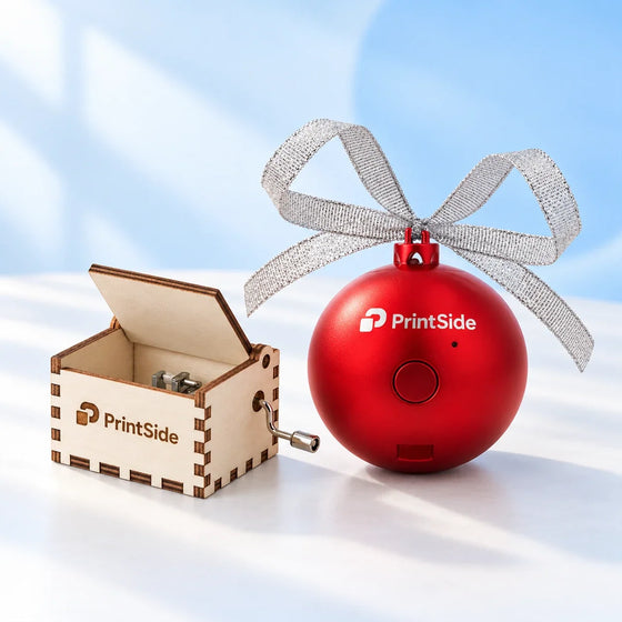 Wooden hand-cranked music box and red bauble speaker with a silver bow and PrintSide logos.
