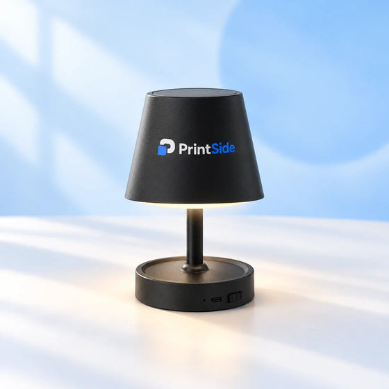 Small black table lamp with a tapered shade and PrintSide logo.