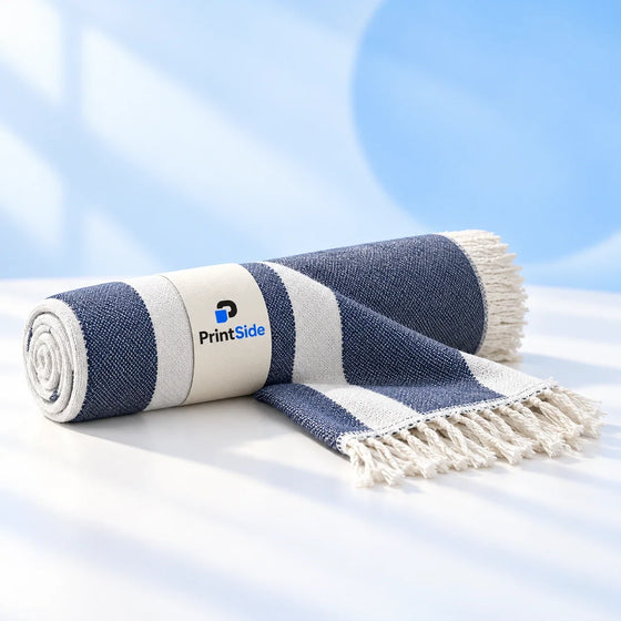 Rolled navy-and-white striped hammam towel with fringe and a PrintSide band.