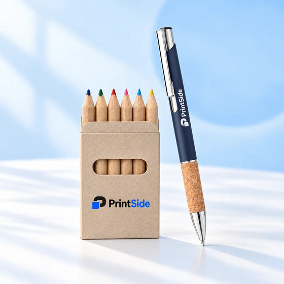 Coloured pencils in a kraft box beside a navy pen, both with PrintSide branding.